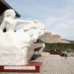 A scale model of the completed Crazy Horse monument with the real thing in the background.